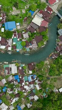 Houses and fishing boats along the Bogac Cold Spring in Surigao del Sur. Philippines. Vertical view.