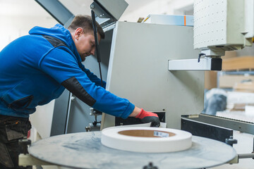 young male carpenter holding a huge tape roll, workshop. High quality photo