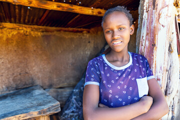 african village, single teenager girl with braids in front of the door outdoors , mud hut interior...
