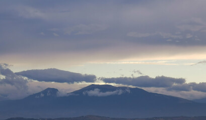 Nuvole bianche e grigie aggrappate come ovatta alle montagne in una giornata invernale al tramonto