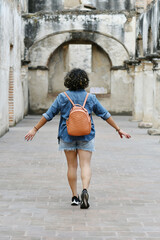 Mujer viajera caminado por un corredor en las ruinas de Antigua Guatemala. Viajera usando pantalones cortos.
