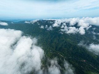 Aerial view flowing fog waves on mountains tropical rainforest,Bird eye view image over the clouds, Amazing nature background with clouds and mountains peaks in Thailand