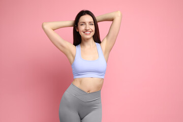 Happy young woman with slim body posing on pink background