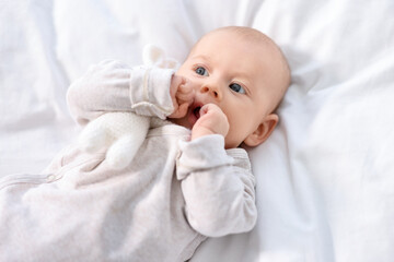 Cute little baby lying on white sheets, top view