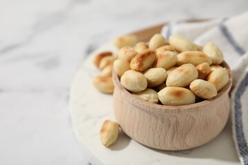 Roasted peanuts in bowl on white table, closeup. Space for text