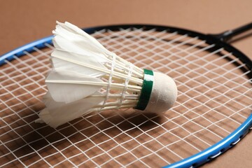 Feather badminton shuttlecock and racket on brown background, closeup