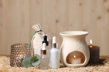 Different aromatherapy products, burning candles and eucalyptus leaves on table