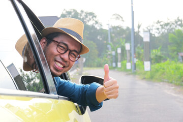 A man smiling and give thumbs up from inside his car