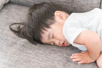 家のソファで昼寝する日本人の男の子
