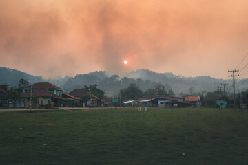 a sunsets as a forest fire burns in the hills