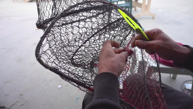 Harbor Fisherman Repairing Fish Catching Cage with Fishing Net Needle Footage.