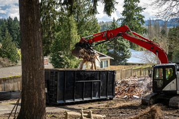 Demolition cleanup and debris removal, heavy equipment with jawbone bucket used to pickup debris and deposit in commercial dumpster for hauling away, residential construction  © knelson20