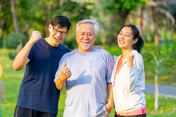 Portrait of Asian couple and elderly father jogging exercise together at park. Retired man with...