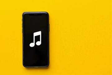 Cell phone with musical note icon on the screen, yellow background