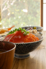 木製のテーブルの上に置かれたサーモンとイクラの親子丼