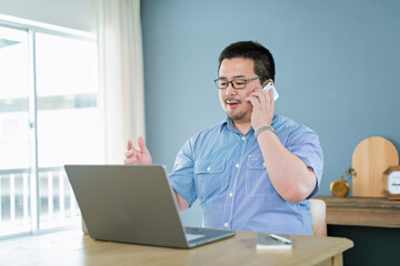 Fototapeta premium パソコンを見ながら電話をする大柄な日本人男性