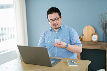 Fototapeta premium パソコンを見ながら電話をする大柄な日本人男性