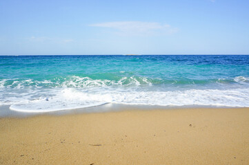 茶色い砂浜に打ち寄せる波の景色