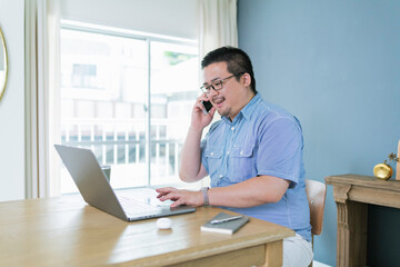 Fototapeta premium パソコンを見ながら電話をする大柄な日本人男性