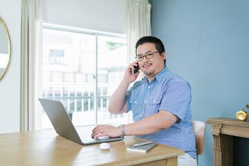 Obraz premium パソコンを見ながら電話をする大柄な日本人男性