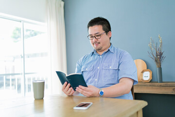休日に自宅で本を読む大柄な日本人男性