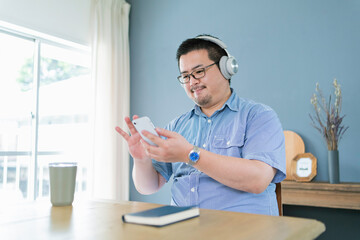 スマートフォンを見ながら音楽を聴く大柄な日本人男性