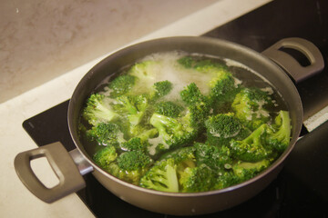 cooking broccoli in pan on electric stove 