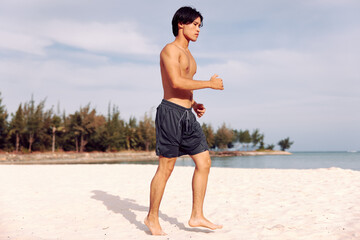 Smiling Asian Man Enjoying Beach Vacation: Torso of a Muscular Guy on Sandy Tropical Island, with...