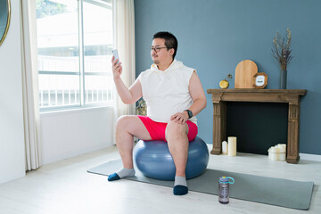 Obraz premium バランスボールに座りながらスマートフォンを見る大柄な日本人男性