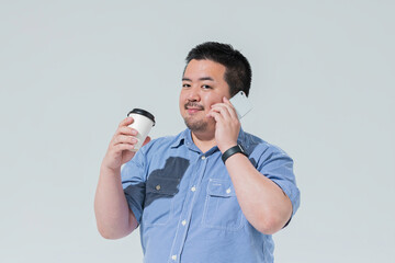 コーヒーを持ちながらスマートフォンを見る大柄な日本人男性