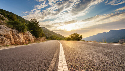 Low level view of empty old paved road in mountain area at sunset; blue cloudy sky; travel concept