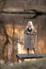 Portrait of a young beautiful blonde girl in a raincoat in the park.