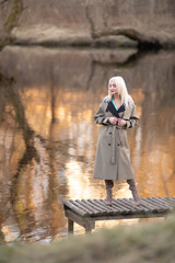 Portrait of a young beautiful blonde girl in a raincoat in the park.