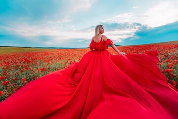 Woman poppy field red dress. Happy woman in a long red dress in a beautiful large poppy field. Blond stands with her back posing on a large field of red poppies