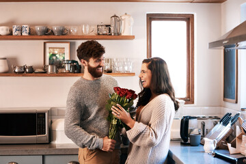 Couple, roses and smile in kitchen for happy, in love and valentines day for support and care on holiday. Man, woman and flower bouquet for surprise and romantic in house for trust, joy or affection