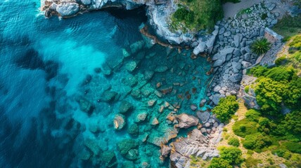 Aerial view of a clear turquoise sea and green grass on a rocky shore in Italy, a beautiful natural...