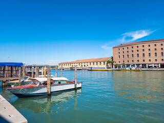 The boat peacefully rests in a serene harbor next to a majestic building, with a tranquil canal...