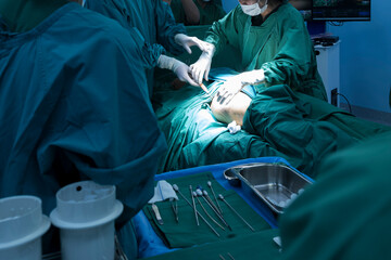 Plastic surgeon sewing up breast of female patient after inserting implants in operating...