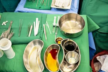 Disinfectant cup set for prepare breast surgery.Plastic surgeon sewing up breast of female patient after inserting implants in operating room.Medical team performing surgery in operation room.