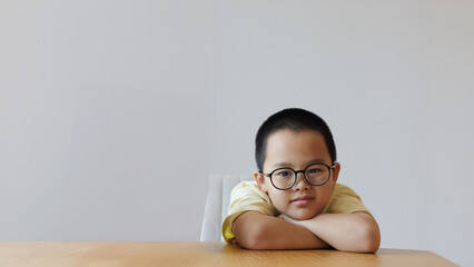 A cute little child wearing glasses sits with his arms crossed and relax expression. copy space,...