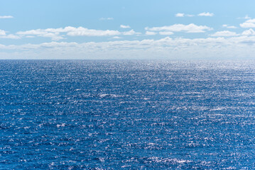 Blue surface of the ocean with gentle ripples on the surface and light reflections.