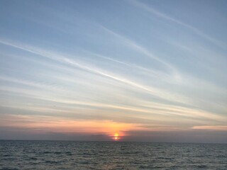 The sun in the twilight sky was about to set near the horizon over the Andaman Sea and smooth sea waves