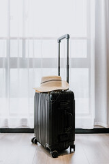 Black suitcase in front of bright curtains