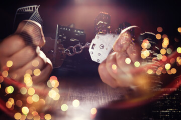 Double exposure of male hands locked in handcuffs with city landscape background, with cross processing filter.