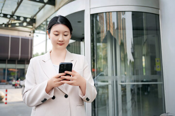 Professional Woman Texting on Smartphone Outside Office