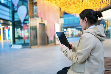 Woman Enjoying Tablet Content in Lively Shopping Area