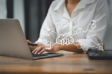 Professional woman working on laptop in office with digital interface showing cloud computing...