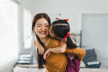 Little girl enjoying a piggyback ride with young mother at living room. Family enjoy playtime...