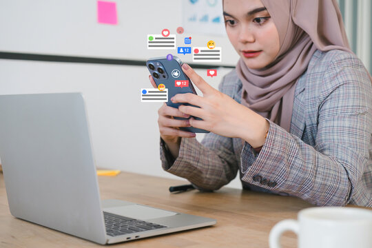 Smiling woman in hijab engaging with social media on smartphone