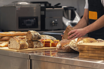 Baker in bakery cutting fresh bread